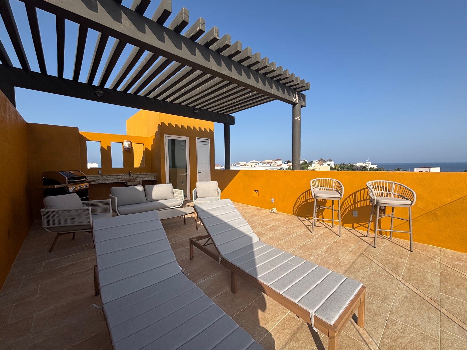 Private rooftop terrace at Casa Solaz with grill, lounge seating, and tall sunset-view chairs